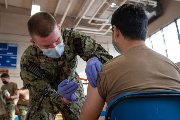 Navy corpsman administers vaccine to sailor