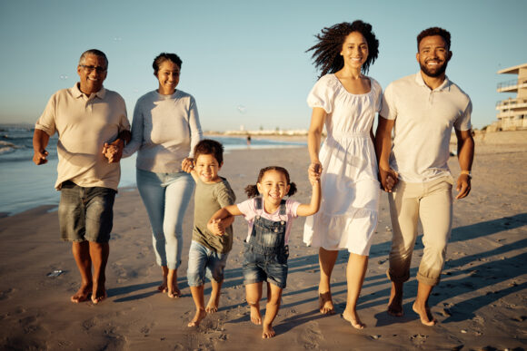 Portrait of happy family with little kids walking together on beach during sunset. Adorable little children bonding with mother, father, grandmother and grandfather outdoor on summer vacation